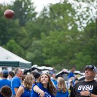 Attendee throws football in parking lot during Family Day tailgate.